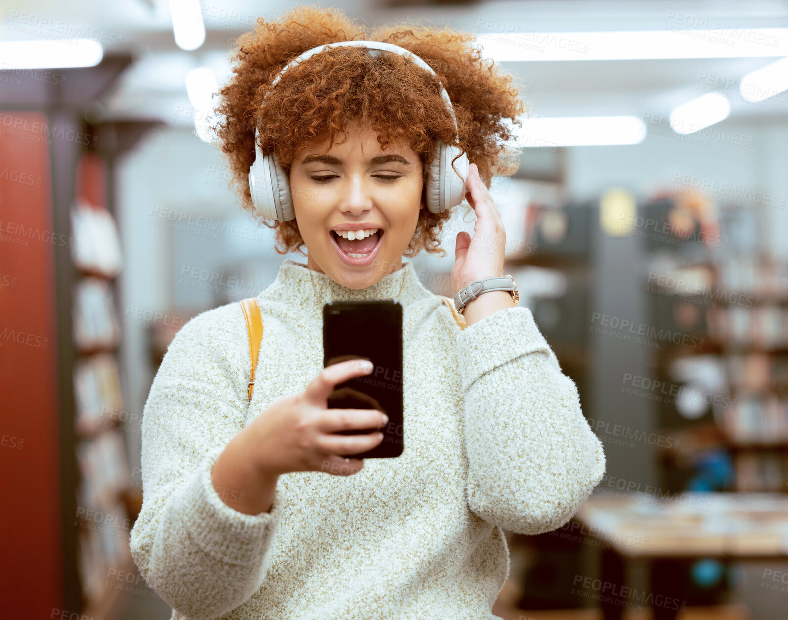 Buy stock photo Headphones, phone and woman in the library with music, radio or podcast for study motivation. Happy, excited and female college student from Brazil listening to song, album or playlist in book store.