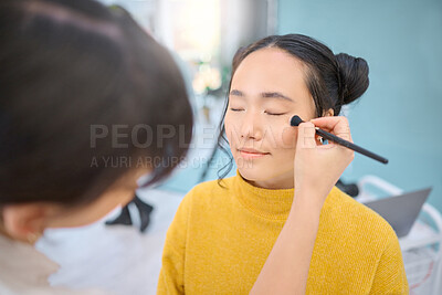 Buy stock photo Beauty, cosmetic and beautician doing makeup on a woman for a creative photoshoot in a studio. Cosmetics, art and stylist preparing a young Asian female model with a routine for a photography job.