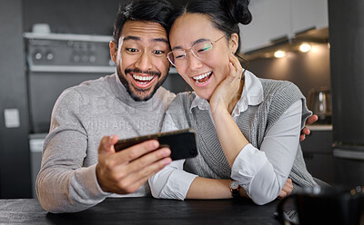 Buy stock photo Love, technology and couple with phone in home kitchen watching funny video online. Social media, wow and surprised asian man and woman with mobile streaming comic movie and laughing at night.