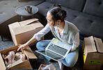 Laptop, real estate and woman moving into new home while unboxing boxes with shoes. Relocation property, computer and top view of Asian female or house owner opening box of footwear in living room.