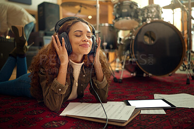 Buy stock photo Music, musician headphones and woman in studio streaming podcast, song or radio online. Relax, meditation and black female artist listening to audio recording while lying on floor with mockup tablet.