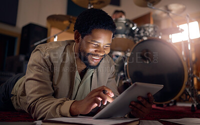 Buy stock photo Black man musician, tablet and technology in music studio for social media, lyrics research or internet browsing. Tech, digital touchscreen and male artist web scrolling or editing audio at night.