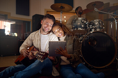 Buy stock photo Guitar, musician couple and tablet in studio for music production or social media. Musicians, diversity love and happy man and woman with acoustic instrument and technology for web scrolling at night