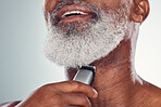 Grooming, skincare and man shaving beard on face isolated on a grey studio background. Cleaning, smile and African senior model with a tool for facial hair removal, hygiene and routine on a backdrop