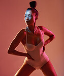 Art, beauty and neon with a model black woman in studio posing in underwear on an orange background. Aesthetic, creative and fashion with an attractive young female standing on a kaleidoscope wall