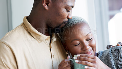 Buy stock photo Kiss, coffee and couple hug by window in home for bonding, commitment and relax together. Marriage, morning and black man and woman embrace for healthy relationship, love and happiness with tea