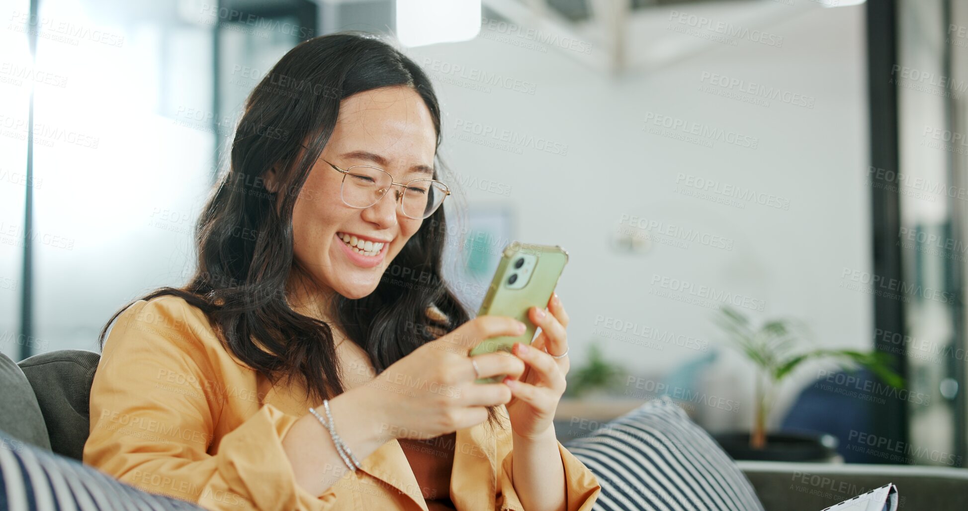 Buy stock photo Asian, woman and reading phone with funny meme, post or communication in chat in home on a sofa with online conversation. Social media, app and person laughing on internet website, email or contact