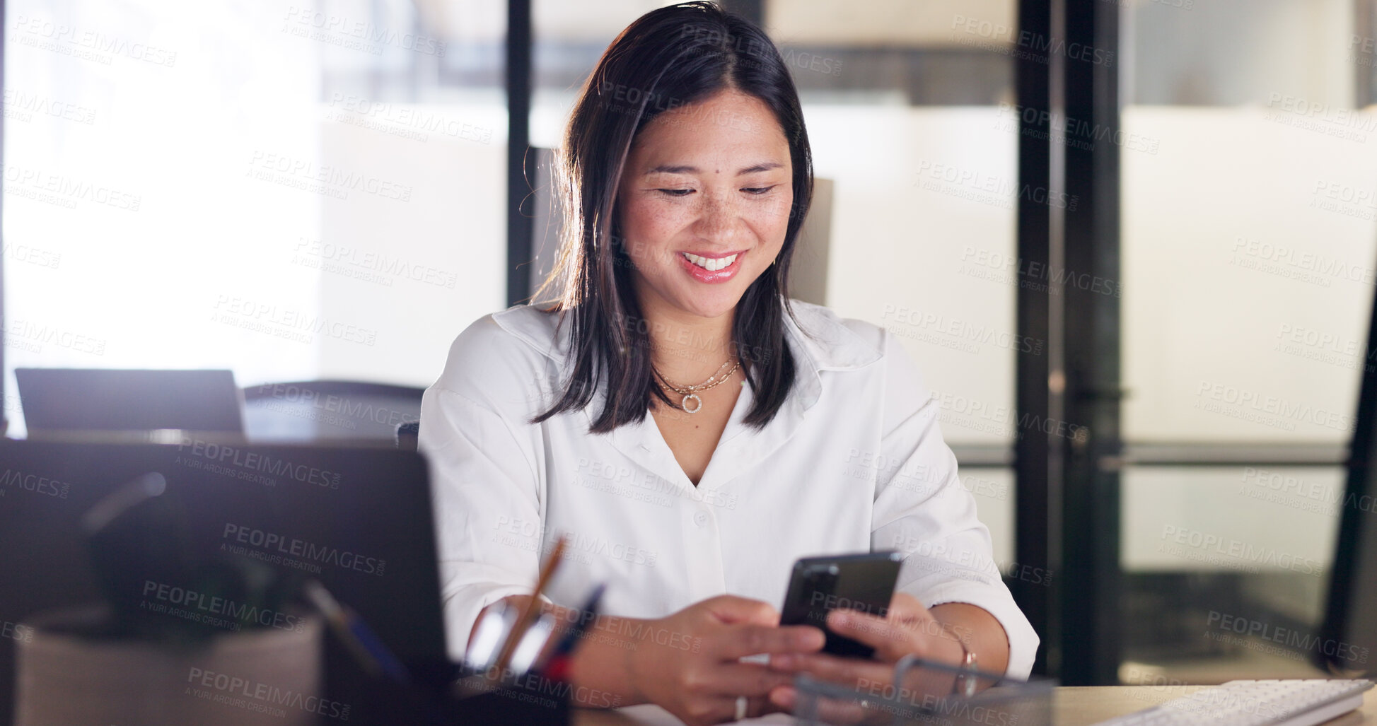 Buy stock photo Phone, communication and a business asian woman at work on her computer for a mobile schedule update in an office. Contact, search and a young employee networking in the workplace for lead generation