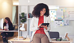 Happy business woman browsing on a digital tablet in a modern office. Confident entrepreneur and cheerful HR manager feeling ambitious and motivated for success while planning project ideas online