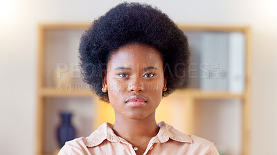 Portrait of a serious african woman at home standing inside her living room. Face of a young trendy female with an afro looking confident and relaxed. Beautiful student with natural makeup staring