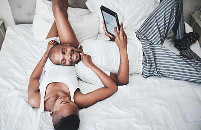 Buy stock photo Black couple, tablet and smile for weekend entertainment relaxing on bed browsing or social media at home. Happy African American man and woman smiling in bedroom on touchscreen for morning streaming