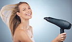 Haircare, hair dryer and beauty portrait of woman in studio isolated on a gray background. Balayage, face and happy female model with hairdryer product for hairstyle, grooming or salon treatment.