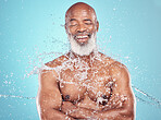 Skincare, happy and senior man in studio for beauty, grooming and water splash on blue background. Elderly, model and guy relax while cleaning, hygiene and skin wellness, hydration and isolated