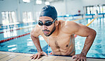 Athletic, breathing and man swimming for fitness, training and race in a stadium pool. Tired, sports and face of an athlete swimmer doing cardio in the water for a workout, sport and competition