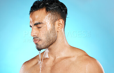 Buy stock photo Shower, skincare and man in studio for water splash, hygiene and grooming on blue background. Cleaning, skin and Mexican model relax with luxury, moisture and wash routine while standing isolated