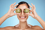 Beauty, skin care and woman with kiwi fruit face for dermatology, natural cosmetic and wellness. Aesthetic model person for sustainable facial glow, nutrition diet and healthy smile blue background