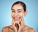 Face cream, skincare portrait and woman in studio isolated on a blue background. Cosmetics, dermatology and happy female model apply lotion, creme or moisturizer for beauty, aesthetics and wellness.