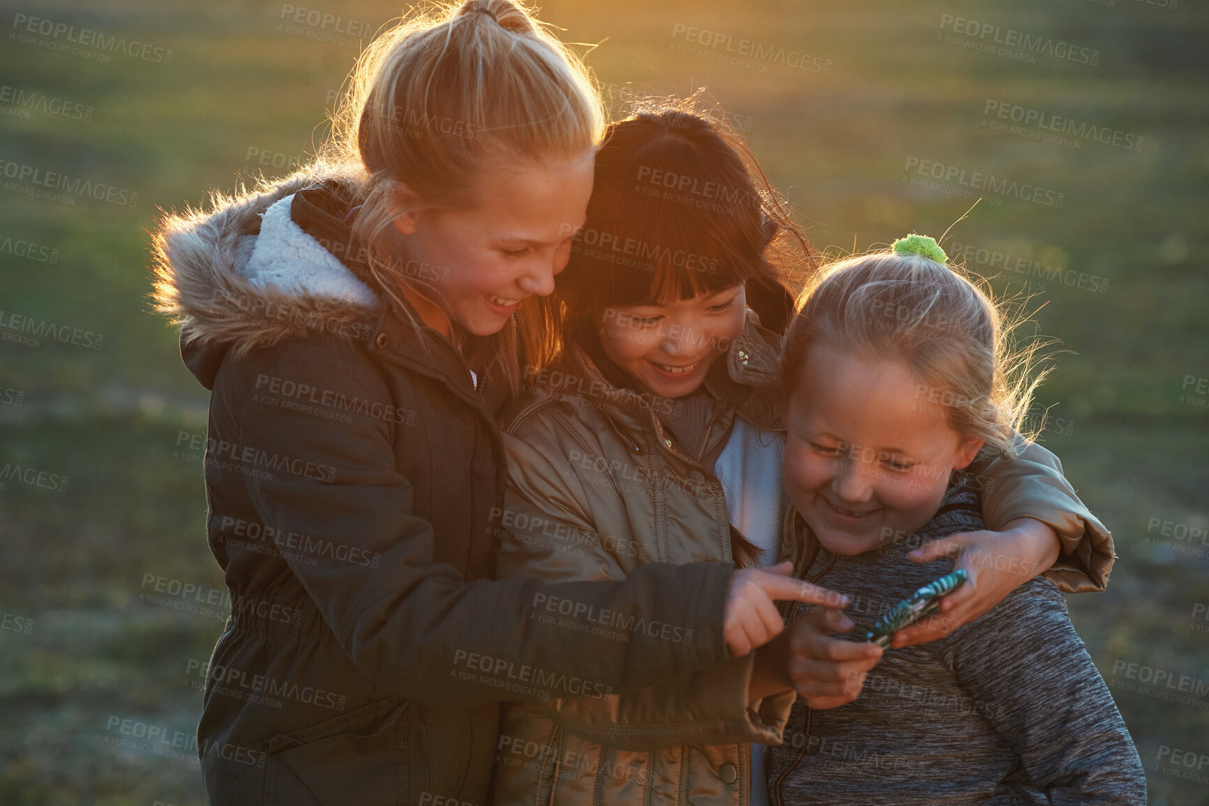 Buy stock photo Friends, girls outdoor and smartphone for connection, online games and happiness on summer break. Young people, female children and kids with cellphone, bonding and watching funny videos on field