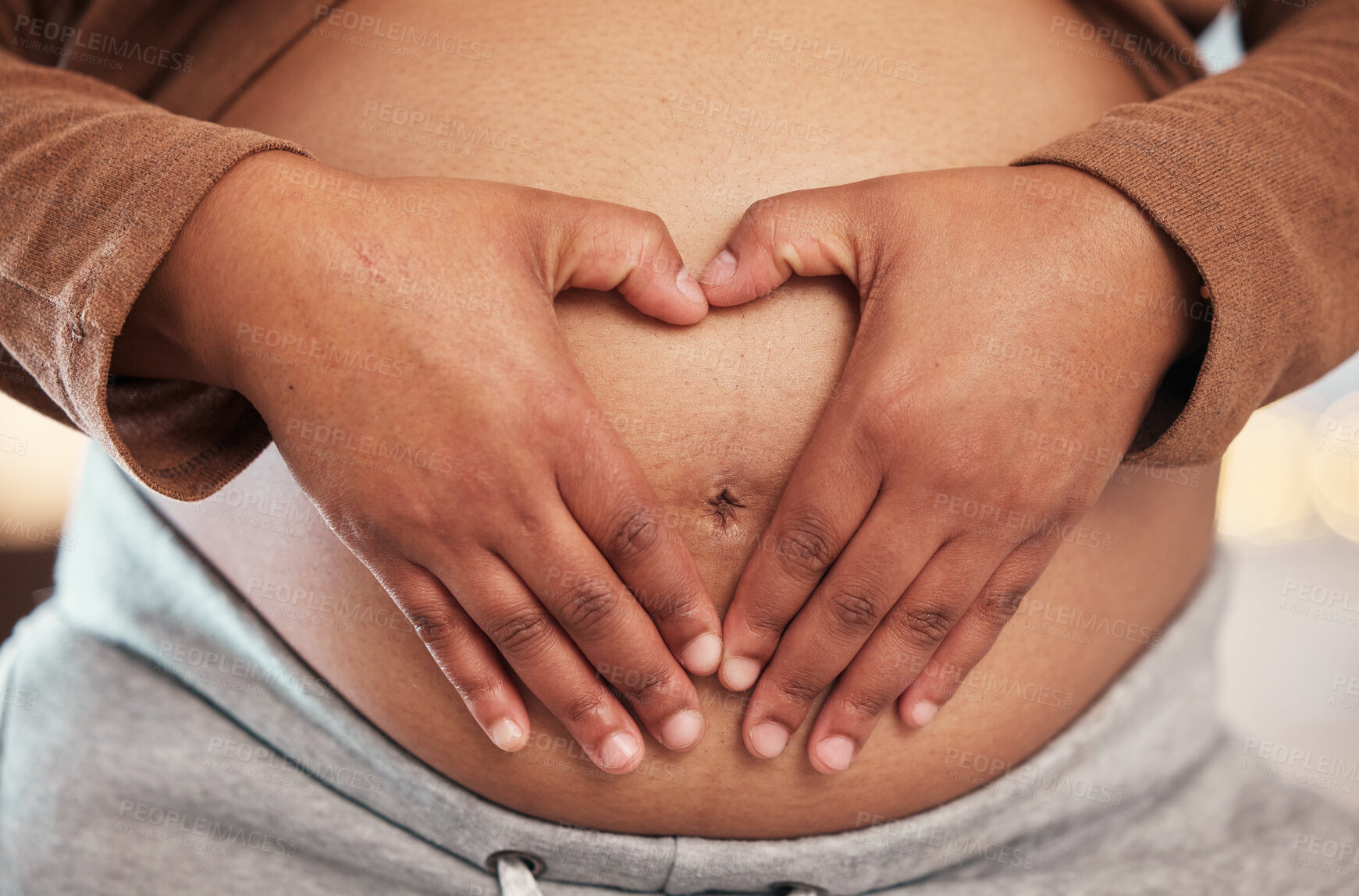 Buy stock photo Pregnant woman, closeup of heart hands on belly and happy black mother alone in Jamaica living room. Excited future parent, holding healthy abdomen at home and loving mommy in pregnancy care