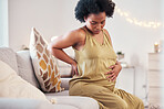 Back pain, spine and pregnant woman with healthcare stress, problem or risk on sofa in her living room. Backache, stomach and pregnancy mother with medical emergency worry, labor or sick on her couch