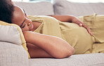 Pregnant, maternity and sleeping woman resting holding her tummy or stomach and relax expecting a baby. Home, pregnancy and lying on a couch or sofa in a house or apartment on a break in a lounge
