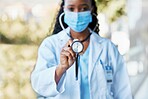 Covid, doctor and stethoscope at hospital with mask for compliance, safety and healthcare on bokeh background. Checkup, corona and female health expert at clinic for help, goal and innovation outside