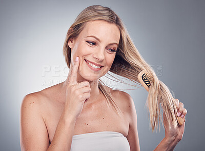 Hair care, thinking and woman brushing her hair in a studio for a keratin, brazilian or botox hair treatment. Pensive, beauty and female model with a brush for a hair style by a gray background,