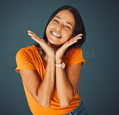 Buy stock photo Woman, happy and hands on face portrait in studio for smile, beauty and motivation for happiness. Model person with orange t-shirt for fashion, positive mindset and mental health on a blue background