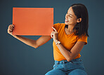 Woman, poster and mockup banner space for sale, discount or promotion. Happy model with advertising for product placement, logo or branding on billboard orange paper sign in studio background
