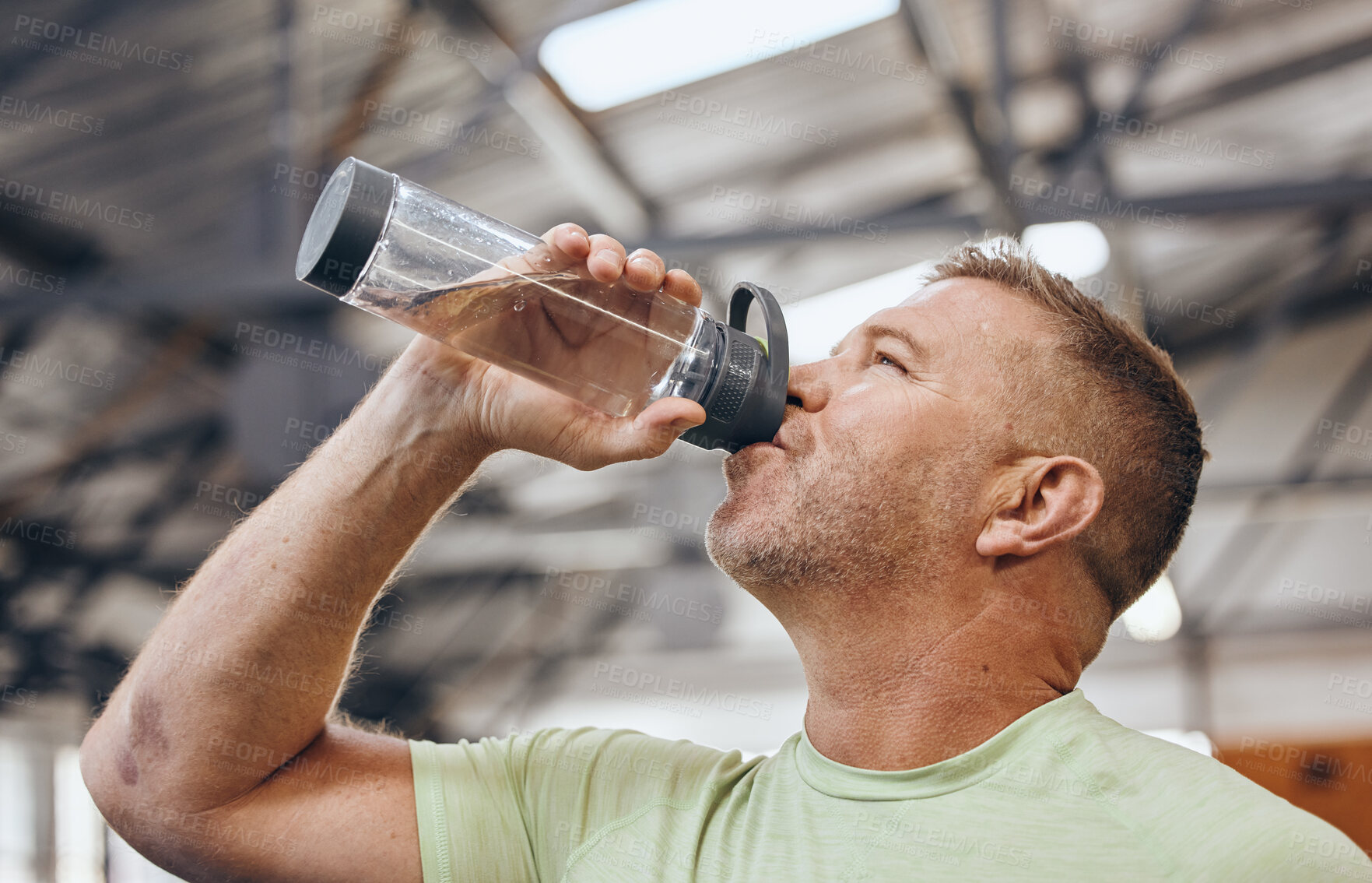 Buy stock photo Man, fitness and drinking water bottle for detox after workout, exercise or cardio training indoors. Sporty male with drink in hydration or healthy endurance, recovery or thirst for sports exercising