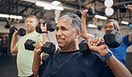 Training, group and senior men exercise together at the gym lifting weights with dumbbells equipment for strength. Elderly, old and fitness people workout in a health club for wellness and health