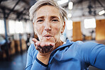 Senior woman, blowing kiss and fitness selfie at gym while happy after exercise, training or workout. Portrait of old person with smile for health, wellness and motivation for healthy lifestyle goals