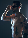 Sports, fitness and body of swimmer in studio with goggles  for wellness, exercise and swimming training. Workout, motivation and man athlete on dark background with muscle, strong body and tattoo