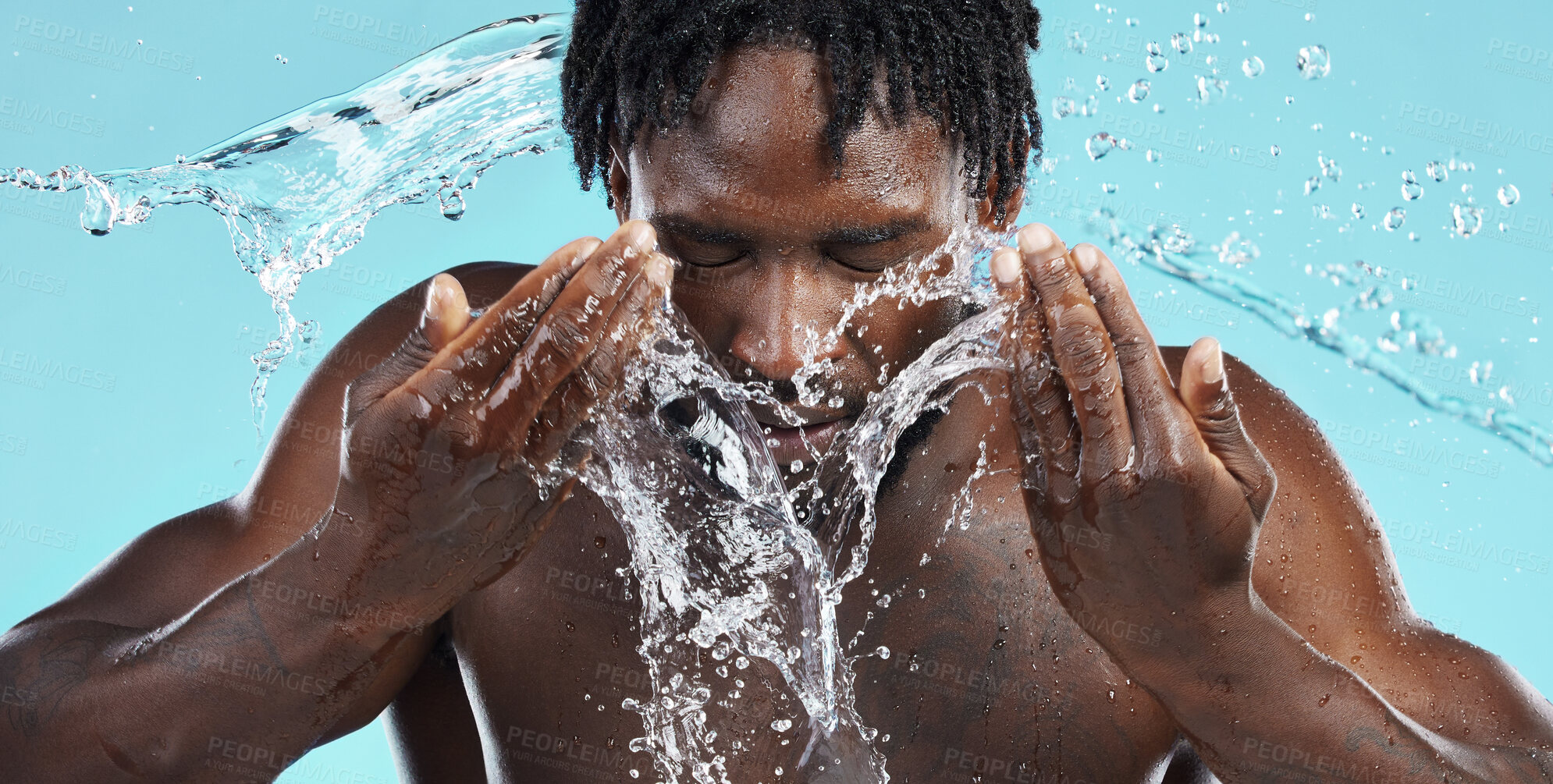 Buy stock photo Water, splash and cleaning face for hygiene with a model black man in studio on a blue background for hydration. Bathroom, skincare or wellness with a male washing himself for natural skin treatment