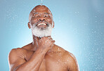 Water splash, skincare and beauty with black man and shower for happy, hygiene and dermatology. Wellness, spa and facial with senior model in blue background studio for health, luxury or hydration