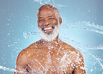 Water splash, portrait and happy man isolated on blue background for face cleaning, shower and beauty skincare. Happy senior model or person with facial wash or body hygiene for dermatology in studio