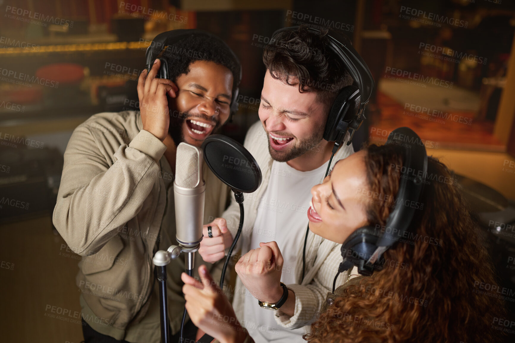 Buy stock photo Music, streaming and diversity, band recording in studio singing into microphone with headphones and talent. Technology, art and creative influencer friends with live stream song for record label.