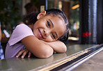 Portrait, cute and adorable girl at a restaurant, cafe and coffee shop with a smile and happy waiting. Kid, child and young person sitting alone in happiness on a weekend in the city or town 