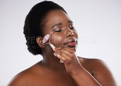 Buy stock photo Black woman, studio and skin, rose quartz roller for cosmetic beauty, smooth and healthy glow on face. Model, happy and skincare massage for health, wellness and beauty by gray background with smile