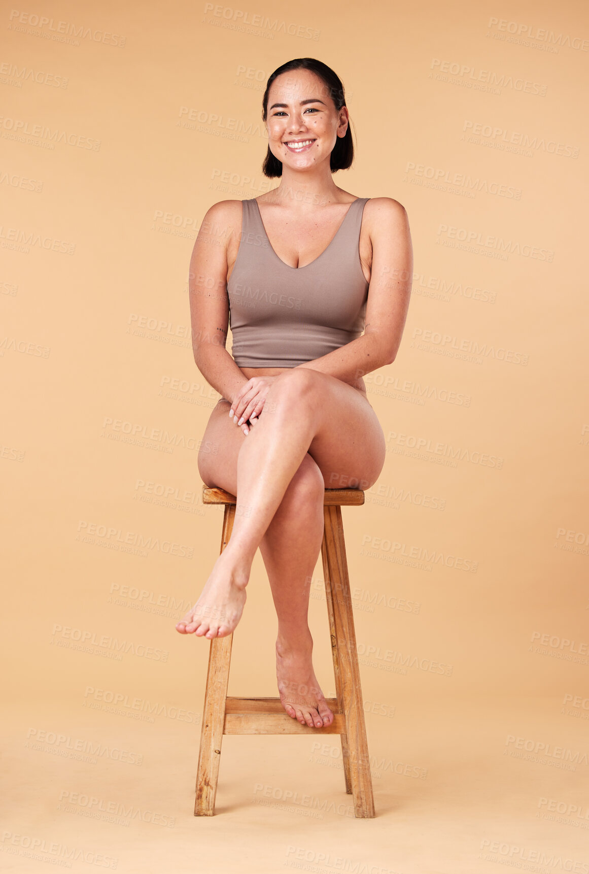 Buy stock photo Portrait, beauty and an asian woman on a chair in studio on a beige background for natural body positivity. Model, underwear and an attractive young female sitting on a stool with confidence