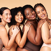 4 Happy Diverse Young Girls in Underwear Hugging Isolated on Beige