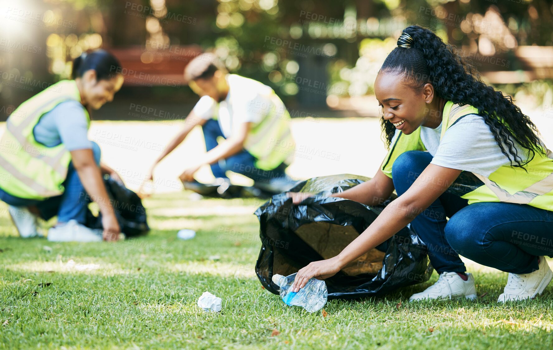 Buy stock photo Volunteer group, nature park and cleaning for community service for clean environment, recycling and pollution. Black woman happy to help people with plastic bottle and trash bag outdoor green grass