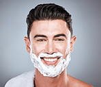 Grooming, shaving and portrait of a man with cream on face isolated on a grey studio background. Happy, hygiene and headshot of a person with a facial product for beard hair removal on a backdrop