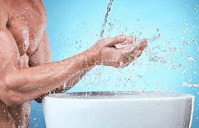 Buy stock photo Water splash, washing hands and cleaning man in studio isolated on a blue background for wellness, healthy skin or hydration. Skincare hygiene, dermatology and male model bathing to remove bacteria.