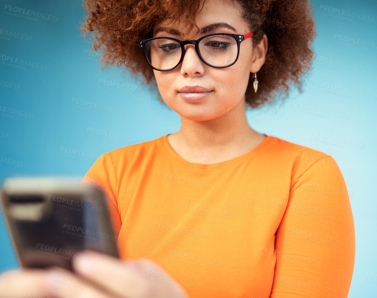 Buy stock photo Woman, cellphone and mobile texting on blue background for social media, technology and network. Young female with smartphone technology in studio for connection, reading notification and website app