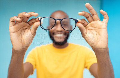 Buy stock photo Hands, glasses and vision with a black man in studio on a blue background for prescription frame lenses. Spectacles, eyesight and eyewear with a male indoor to promote new round frames for seeing
