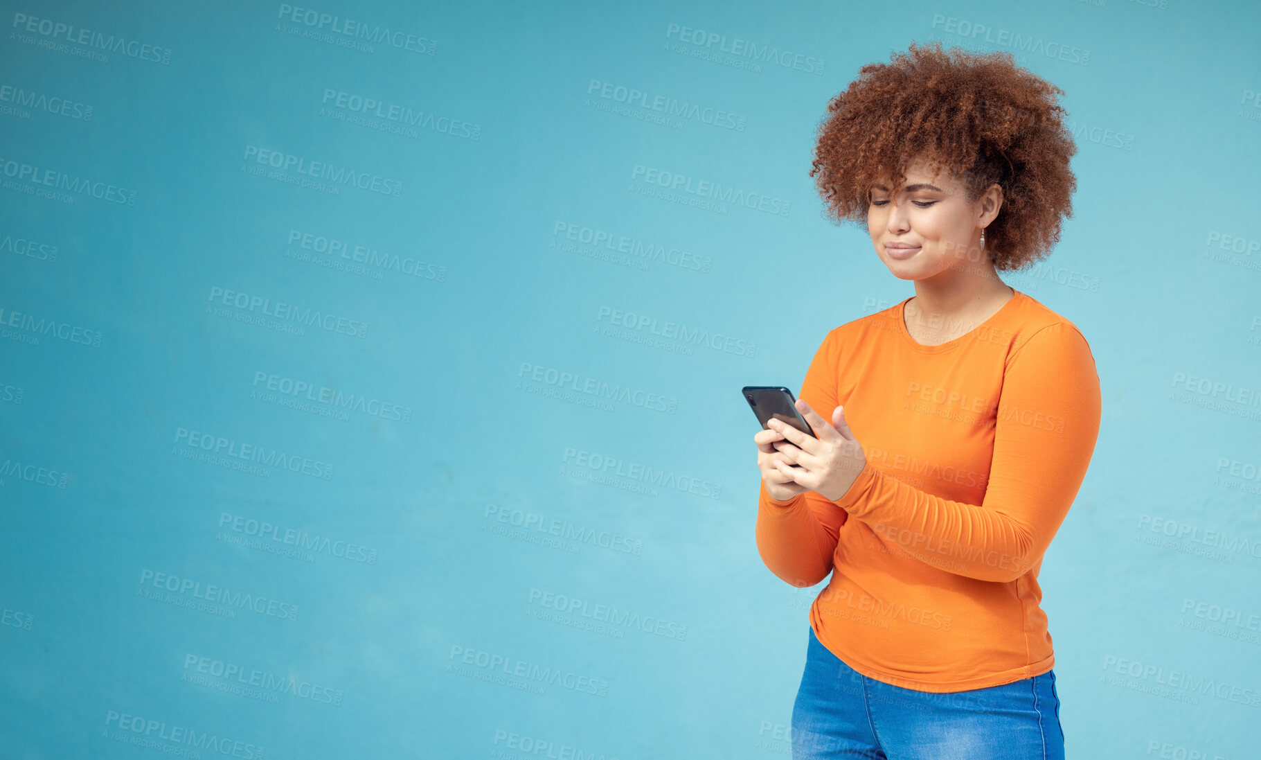 Buy stock photo Woman, cellphone connection and mockup on blue background for social media, website and network. Young female typing on mobile technology in studio for online advertising, marketing app and contact