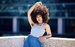 Portrait, fashion and underarm with a black woman in the city on a bridge, looking relaxed during summer. Street, style or urban and a natural young female posing outside with an afro hairstyle