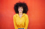 Portrait of happy woman with natural hairstyle on red background, headshot of model and red copy space. Confident young person with serious expression, curly hair and aesthetic fashion on studio wall