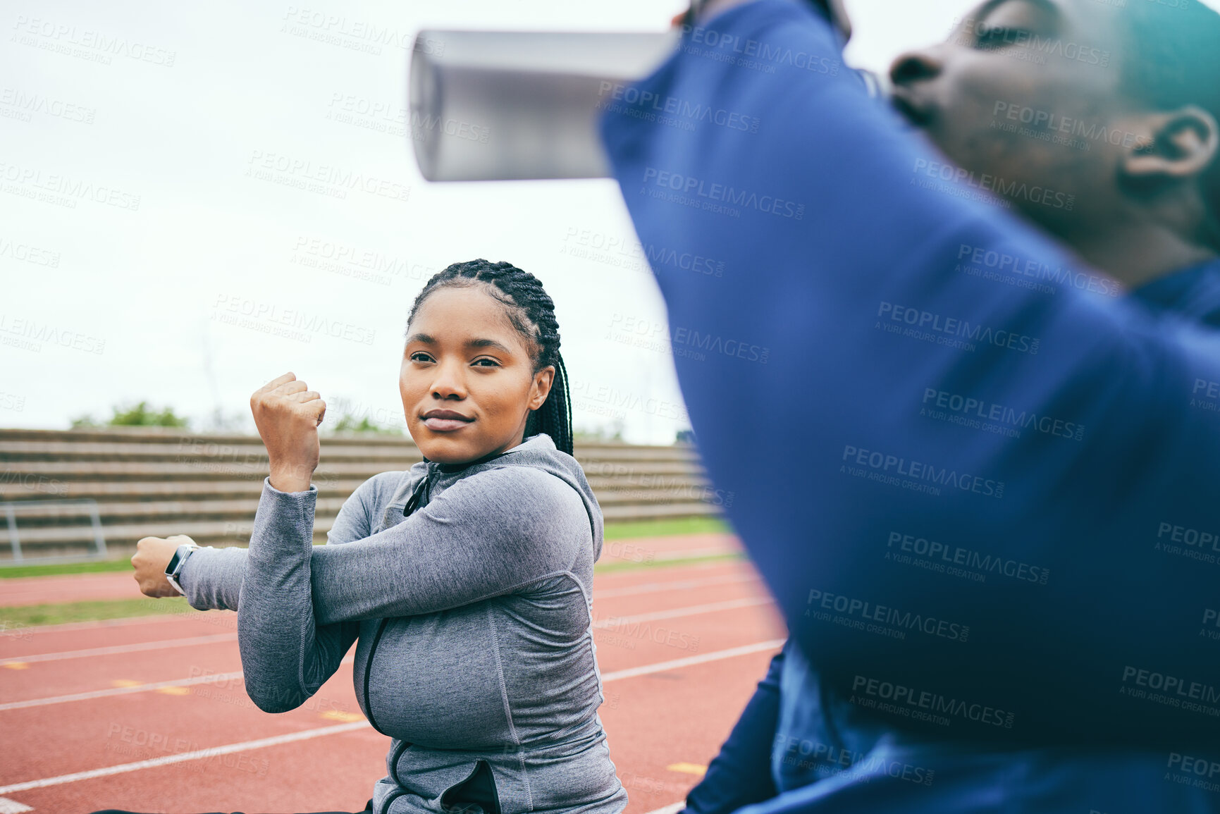 Buy stock photo Running, sports and black woman stretching on race track for exercise, marathon training and fitness. Stadium, workout and athlete team warm up, drink water and ready for challenge, run and racing